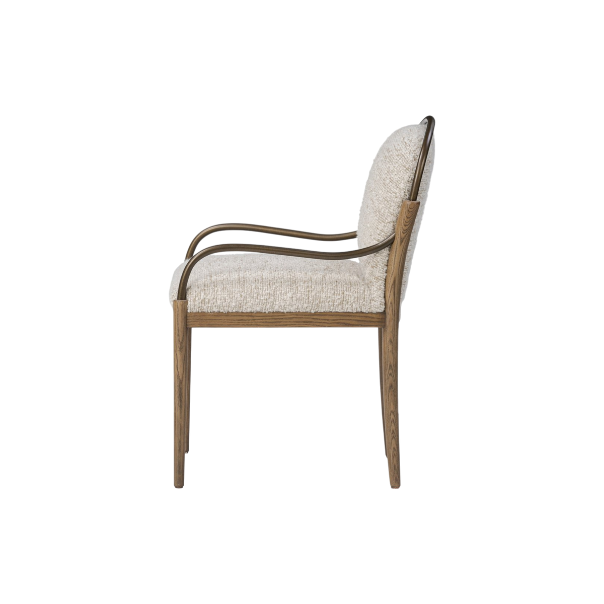The Delfino Arm Chair shown from the side in ivory boucle, its burnished brass armrest sweeping down from a rounded back into a tapered ash wood leg.