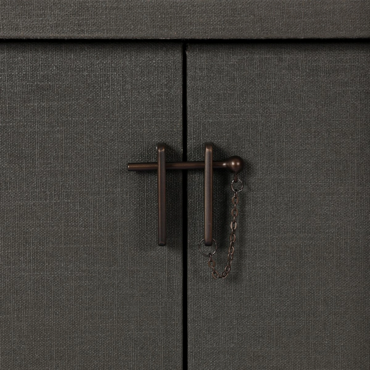 Detail of the Fletcher Sideboard bronze T-bar latch with decorative chain against the textured moss green lacquered linen doors.