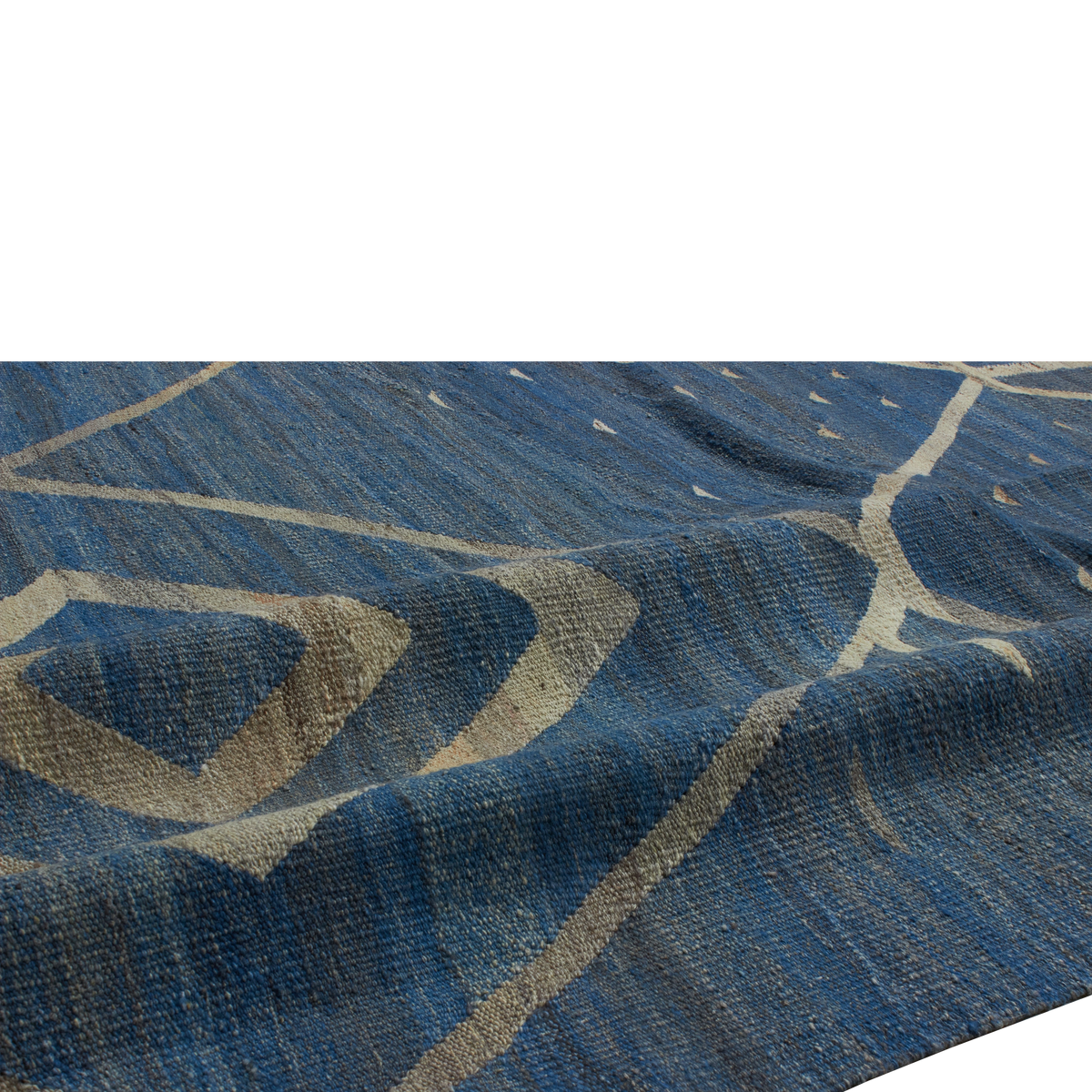 A close-up of a textured blue rug with a beige geometric pattern, shown draped to highlight its woven texture and design.
