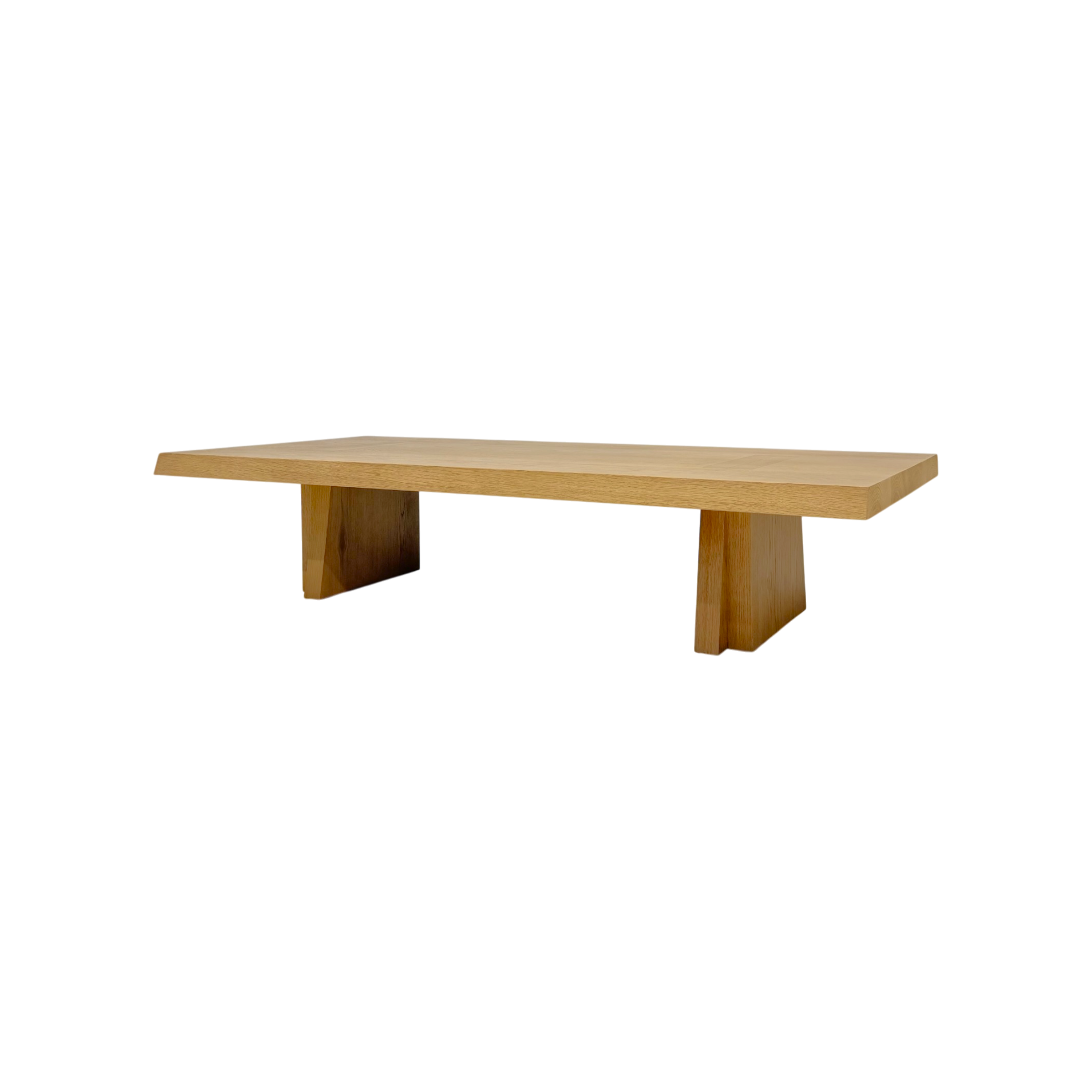 A minimalist wooden coffee table with a light oak finish and block-style legs, shown against a solid white background.