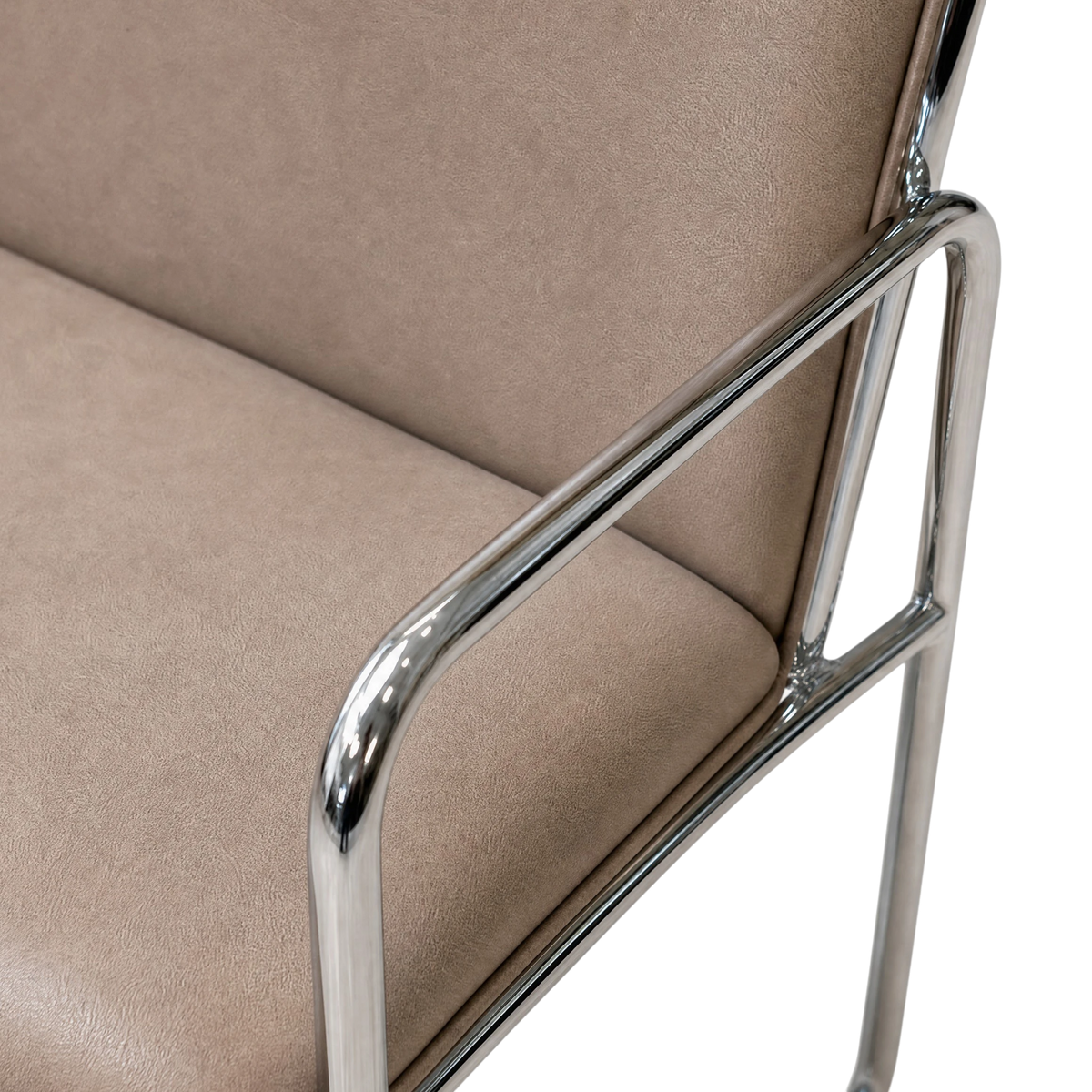 Close-up of a modern chair corner showing a beige upholstered seat and back with a polished chrome metal armrest frame on a white background.