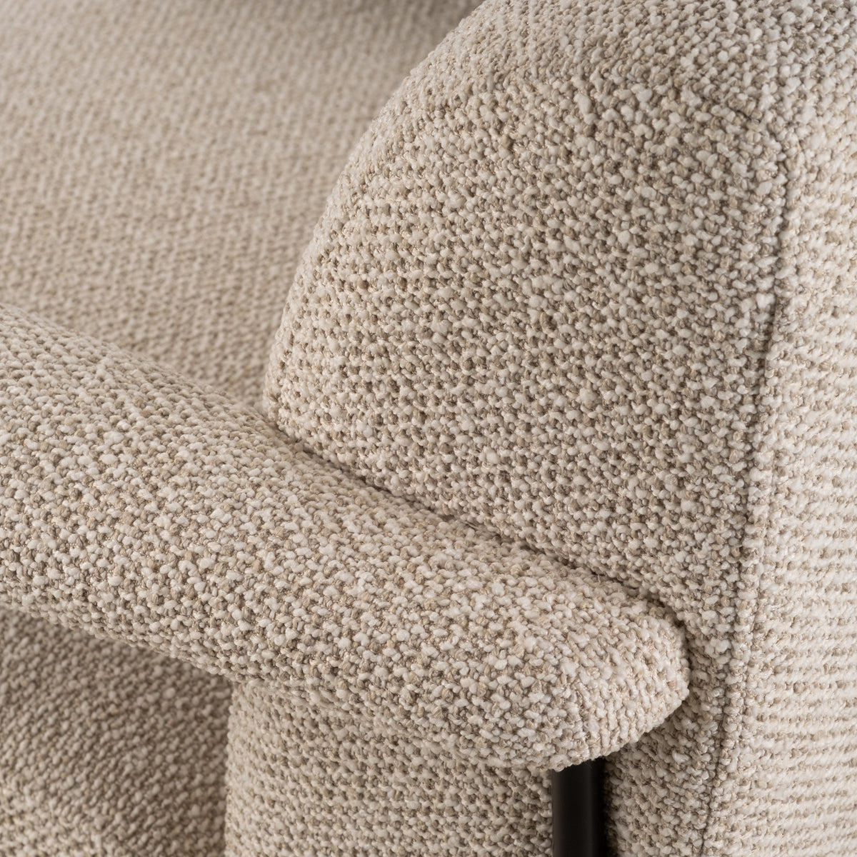 Close-up showing the arm and side of the Knox Lounge Chair in oatmeal woven fabric, with piped edges, a nubby texture, and a black metal post below the arm.