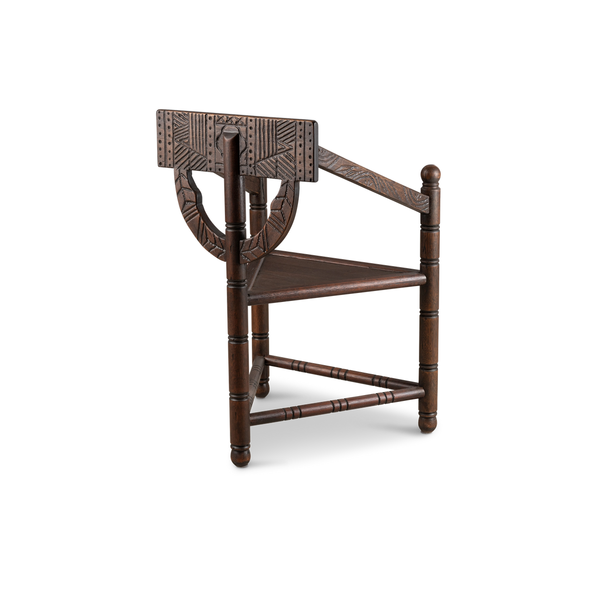 Larkhaven Accent Chair angled from the back in dark brown oak, showing the carved geometric back panel, curved lower crest, and triangular seat on turned legs.