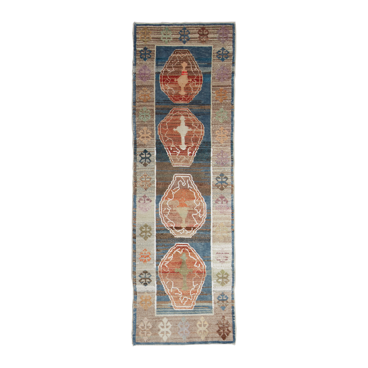 A long rectangular area rug with a distressed tribal pattern, featuring four large central medallions in rust red, orange, and beige on a blue and gray background with cream and pink accents.