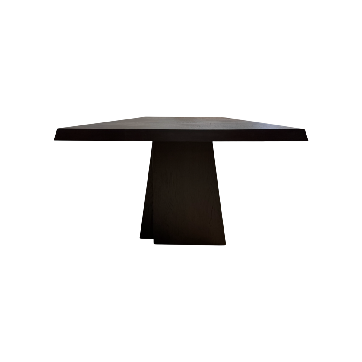 Side view of the Oblique Dining Table highlighting the substantial tabletop and architectural tapered pedestal base.