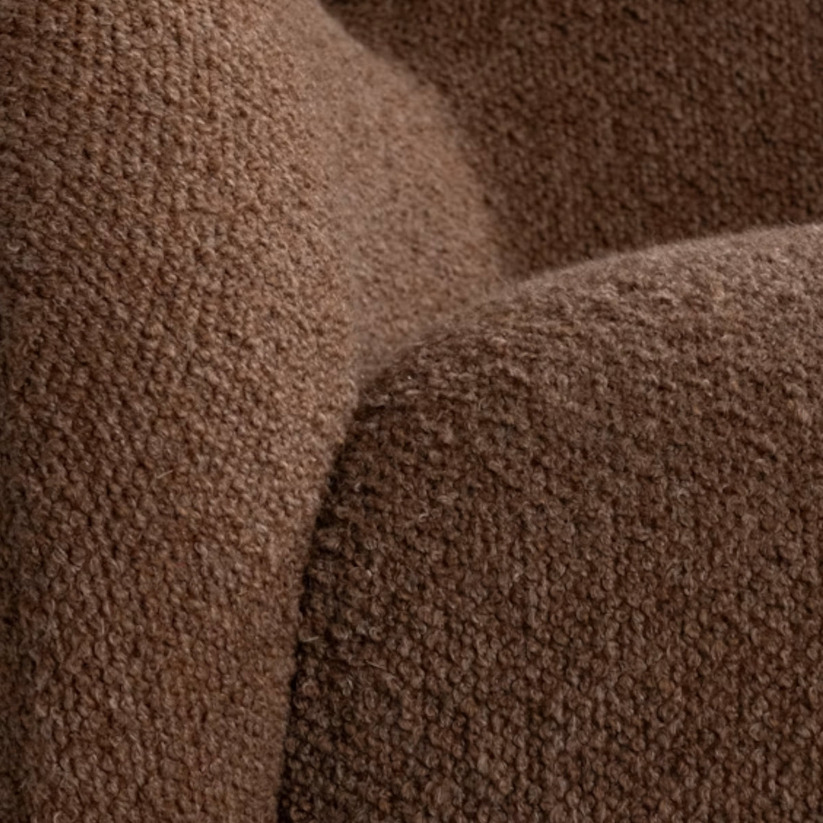 Close-up showing the Tucci Swivel Chair's toffee boucle upholstery, its dense heathered texture and subtle tonal variation catching the light.