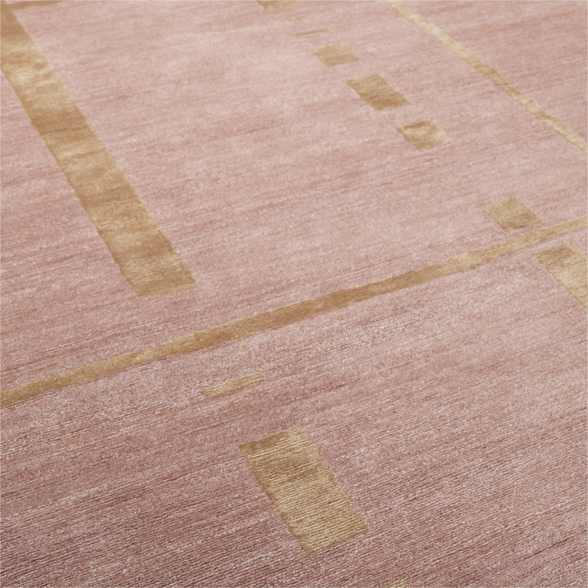 A close-up of a textured area rug in dusty pink with geometric patterns of muted gold and beige lines.