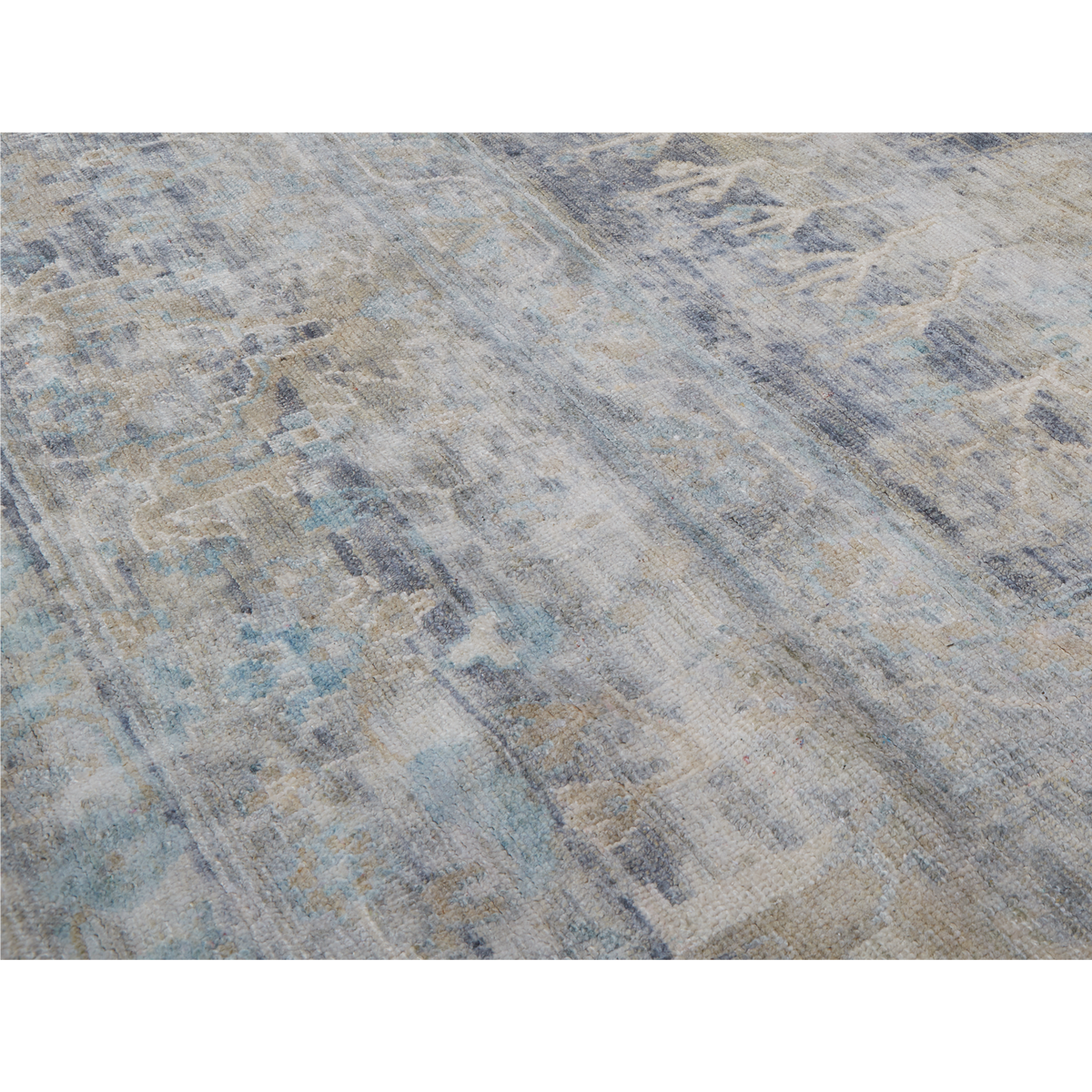 A close-up of a distressed area rug with an abstract pattern in shades of blue, beige, gray, and white.