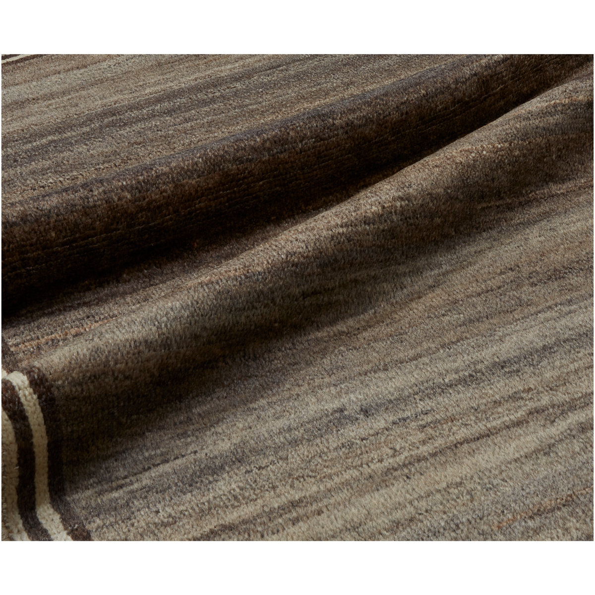 A close-up of a textured woven fabric with a heathered pattern in shades of brown, gray, and beige, draped in soft folds.