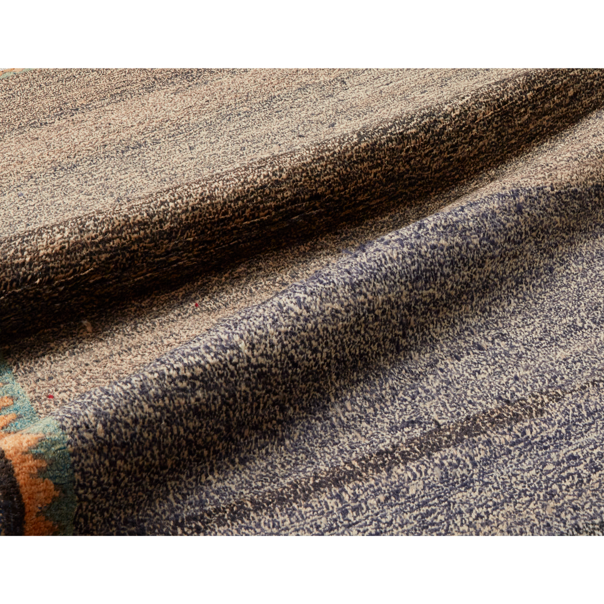 A close-up of a textured area rug with a heathered pattern in charcoal gray, beige, and brown, showing the pile and weave detail.