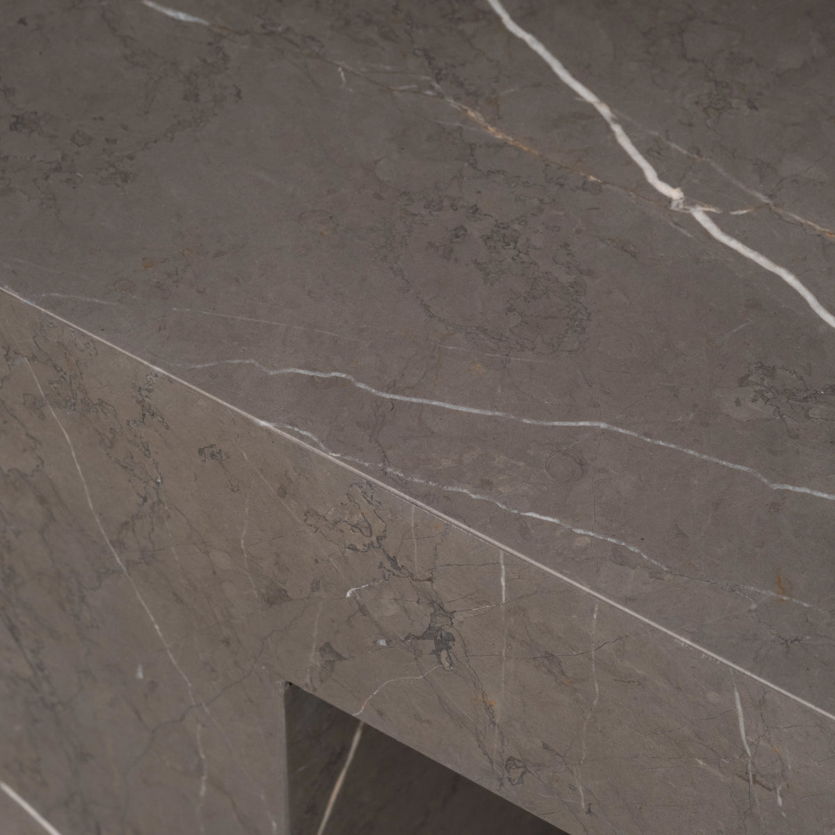 Duvall Coffee Table close-up of a corner in warm gray Petra Grey marble, highlighting the mitred edge and white veining that wraps from top to side.
