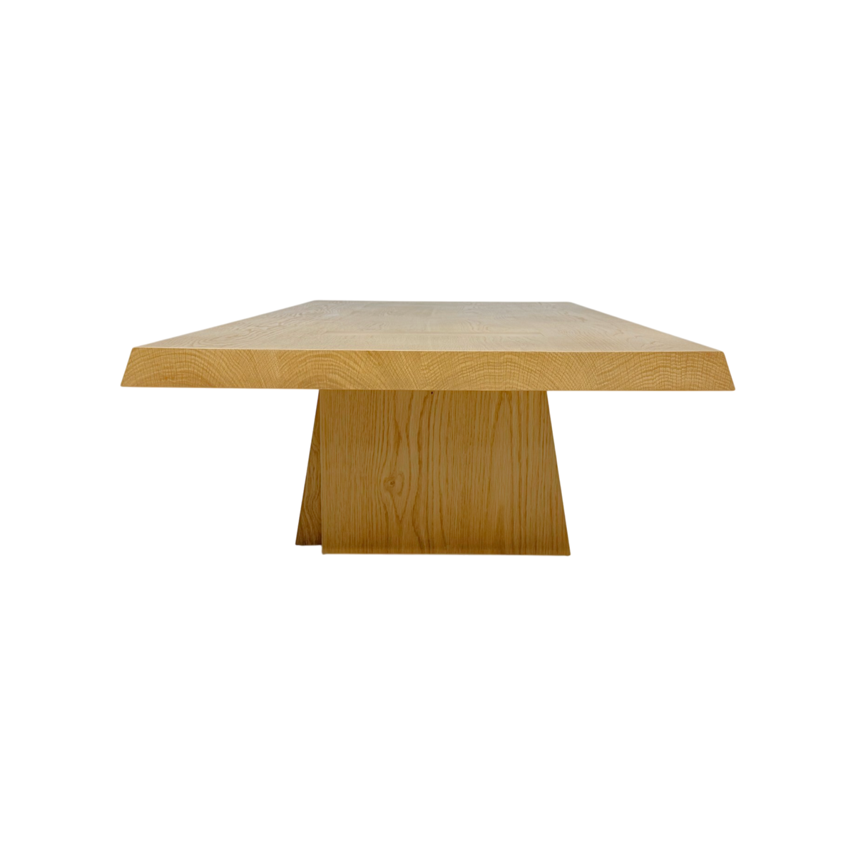 A modern rectangular coffee table made of light oak wood, featuring a thick top and a sculptural wedge-shaped pedestal base, shown against a plain white background.