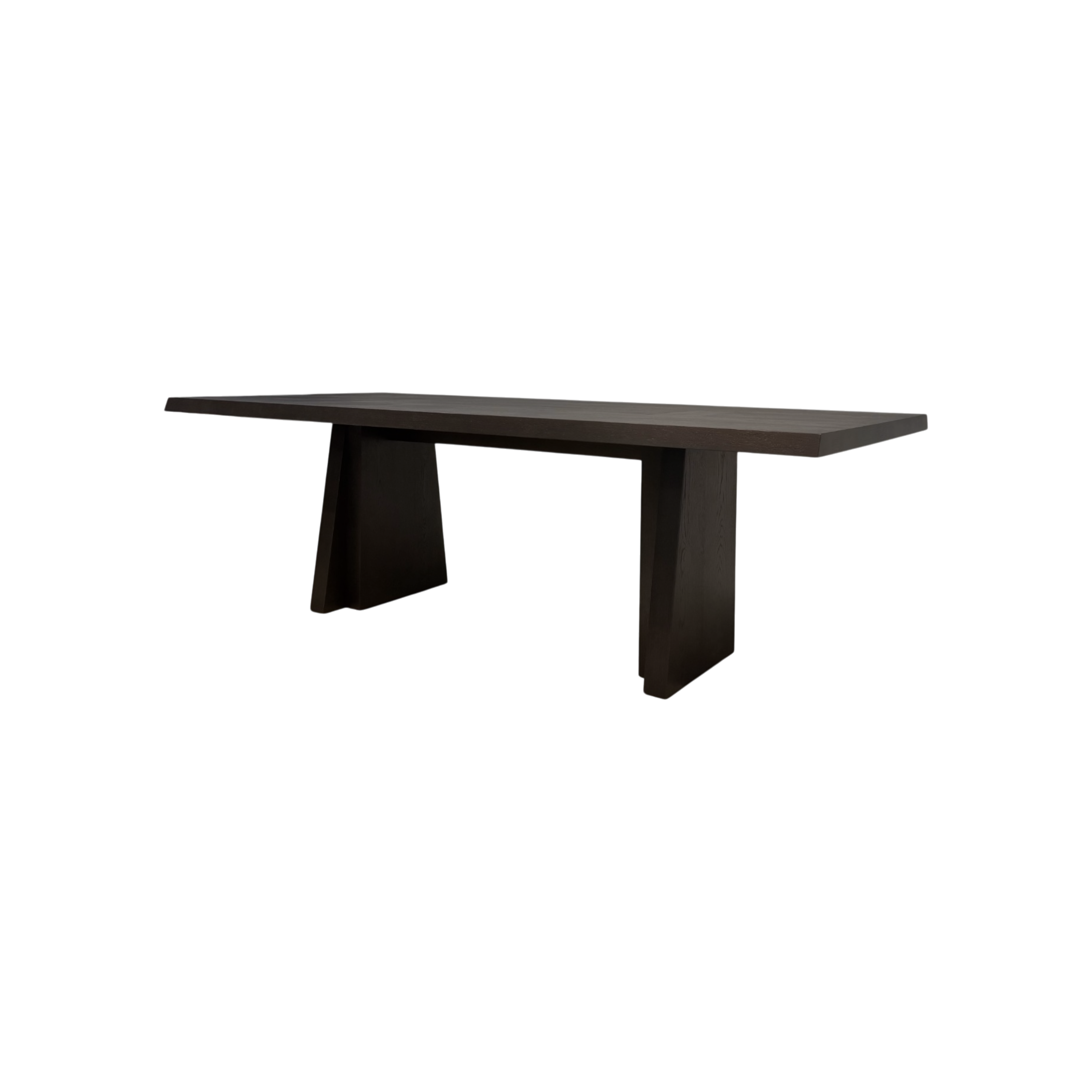 Angled view of the Oblique 120-inch Dining Table showing its elongated dark wood top, chamfered edges and sculptural splayed pedestal bases.