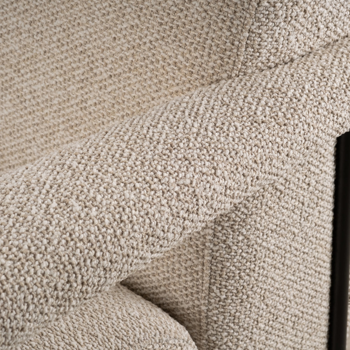Close-up of the Knox Lounge Chair’s padded arm and back in oatmeal bouclé-style fabric, with chunky cream nubs and a black frame upright at the edge.