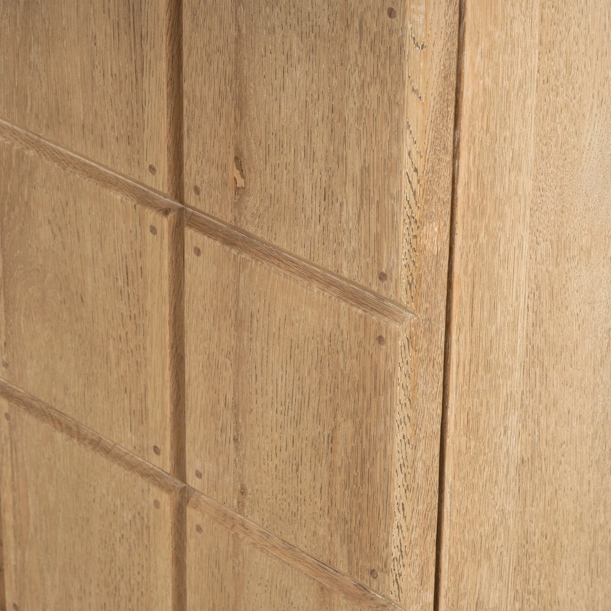 Close-up of the Rosedale Cabinet’s raised grid panels in light tan oak, showing beveled edges, small peg details, and a natural knot.