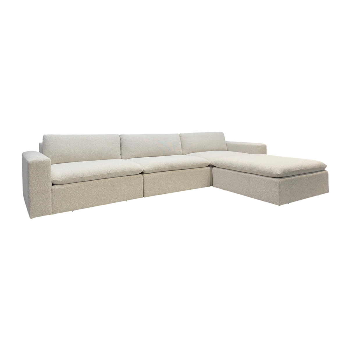 Tempo Modular Sectional in a three-quarter view with ivory textured upholstery, deep cushioned seating, clean-lined arms, and a spacious chaise configuration.