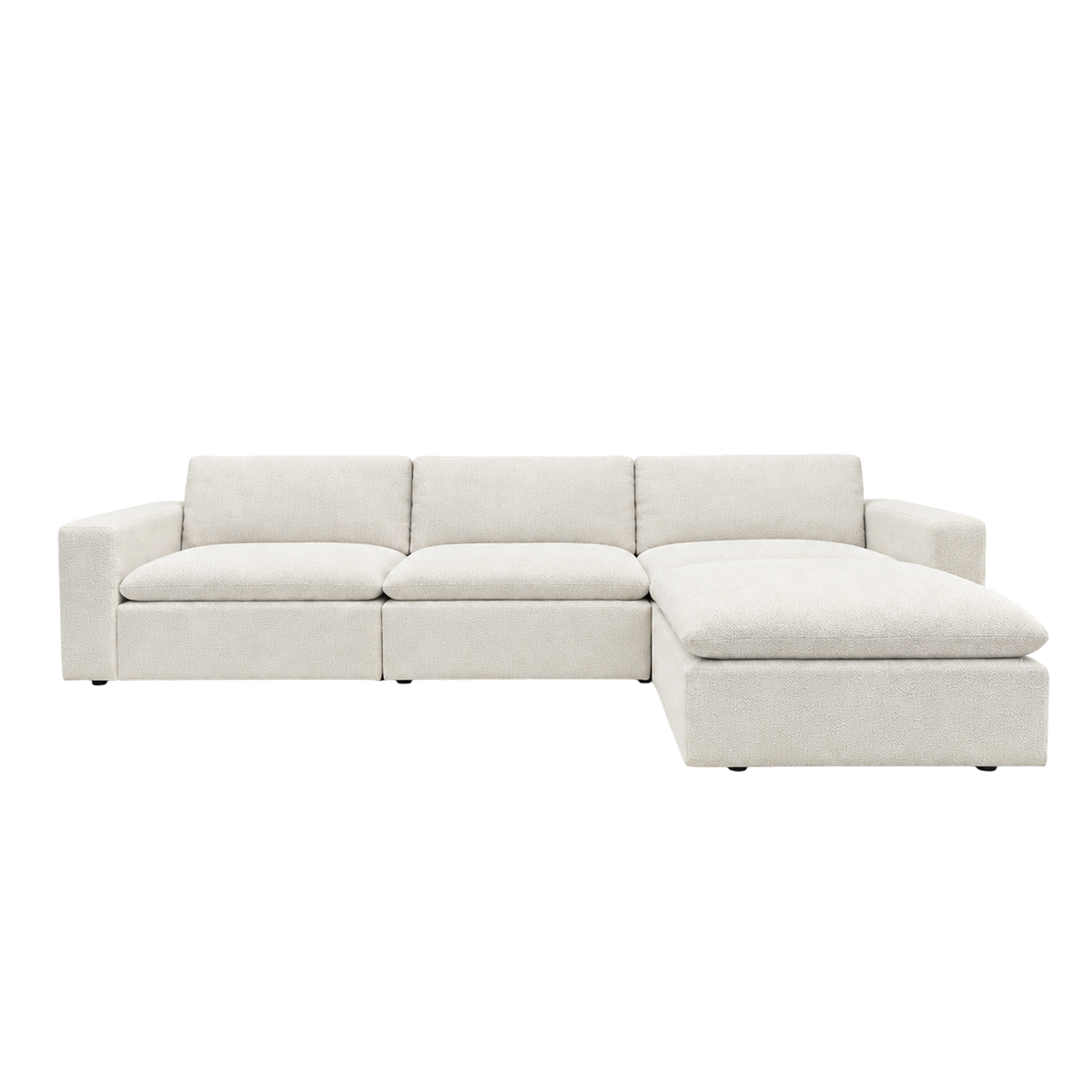 Tempo Modular Sectional shown from the front in heathered greige textured upholstery, with wide arms, three loose back cushions and an ottoman extending the right end into a chaise.